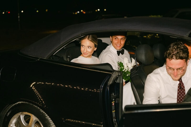 Happy bride and groom in a luxury car at night celebration.