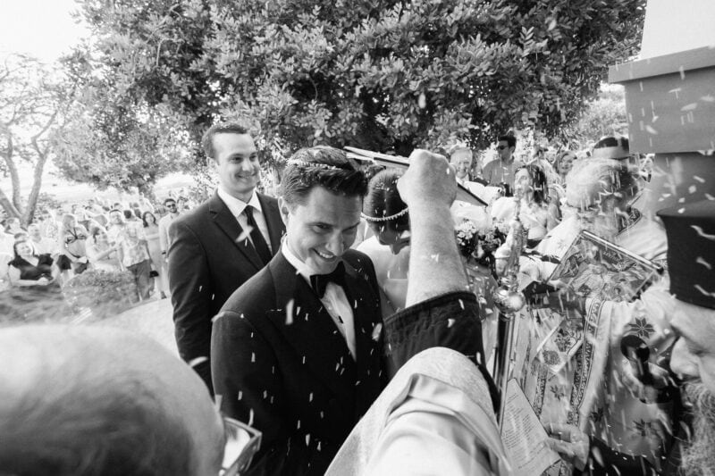 Groom at a celebration event with smiling guests throwing rice