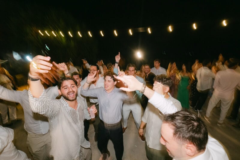 Group of people dancing and celebrating at an outdoor party at night.