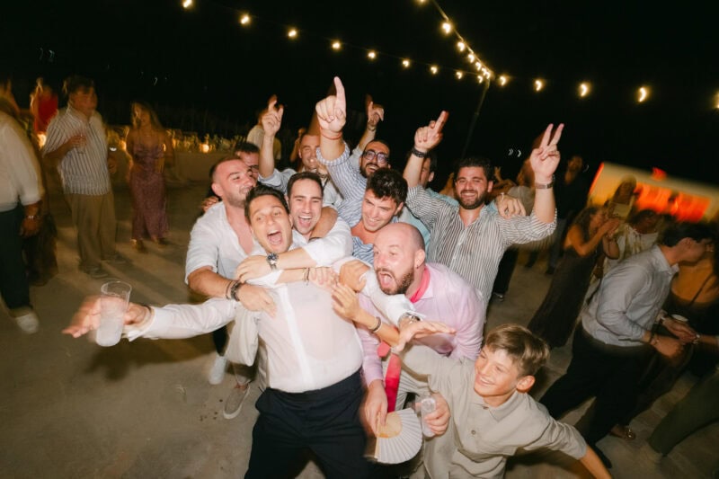 Group of people celebrating at night with lights and joyful expressions.