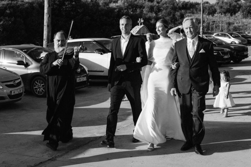 Wedding scene with four people walking outdoors, black and white photo.