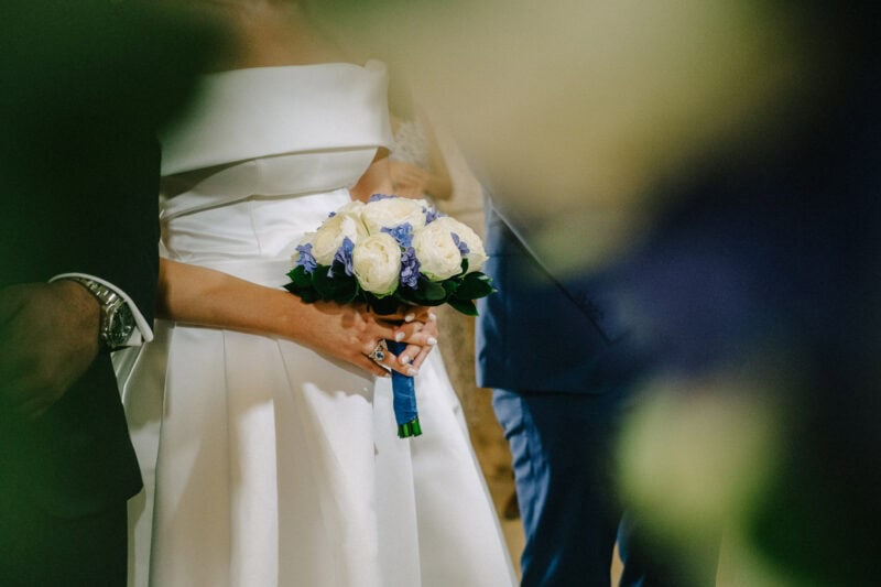 Bride holding a blue and white bouquet during the wedding ceremony in Pylos