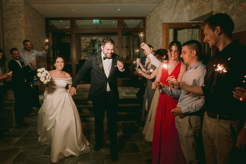 Newlyweds entering their evening reception surrounded by guests holding sparklers