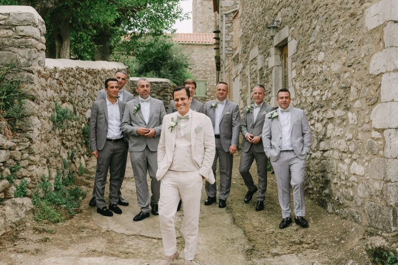 Groom and groomsmen walking through a traditional Mani village