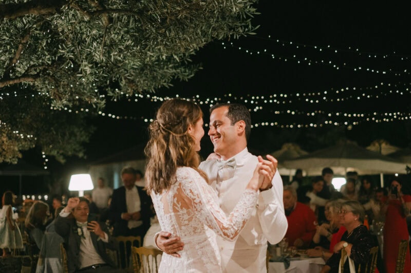 Bride and groom sharing their first dance under string lights