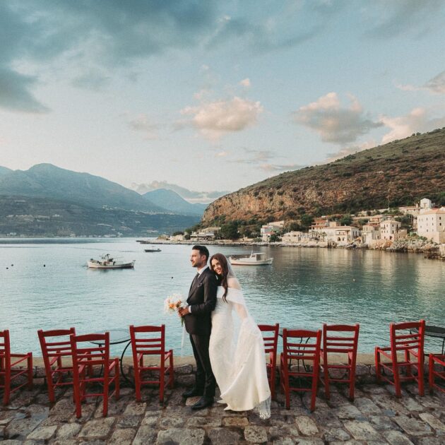 Couple at a scenic Mani waterfront during wedding ceremony.