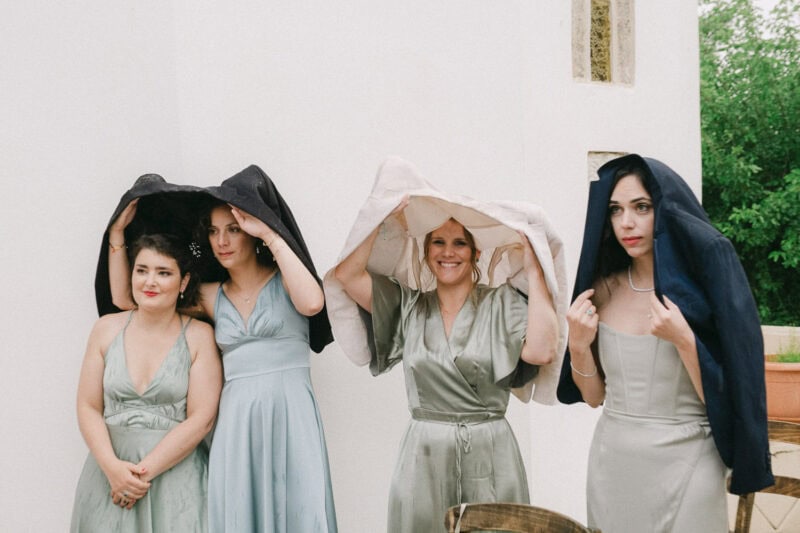 Bridesmaids sheltering from the rain during a Mani wedding