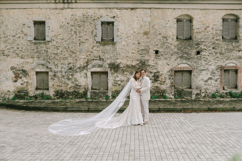 Bride and groom portrait against traditional stone architecture in Mani