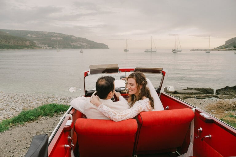 Newlyweds embracing in a vintage car by the sea in Mani