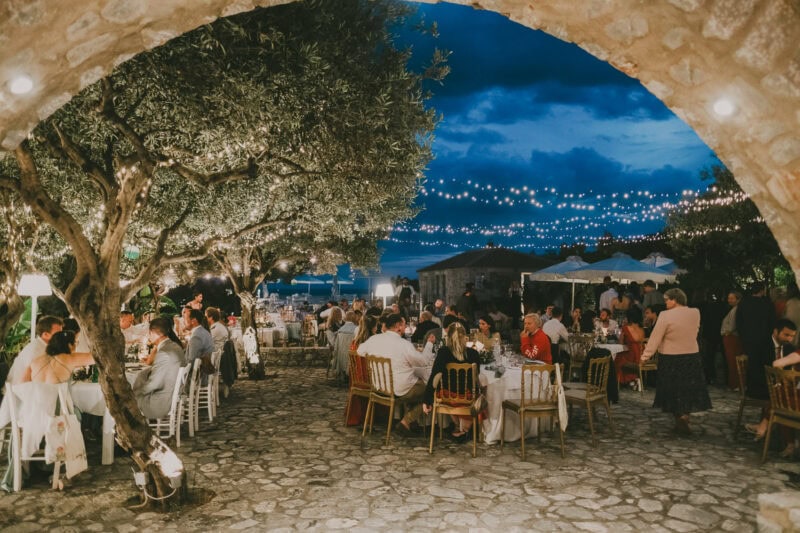 Outdoor wedding reception beneath an olive tree at Porto Vitilo in Mani Greece