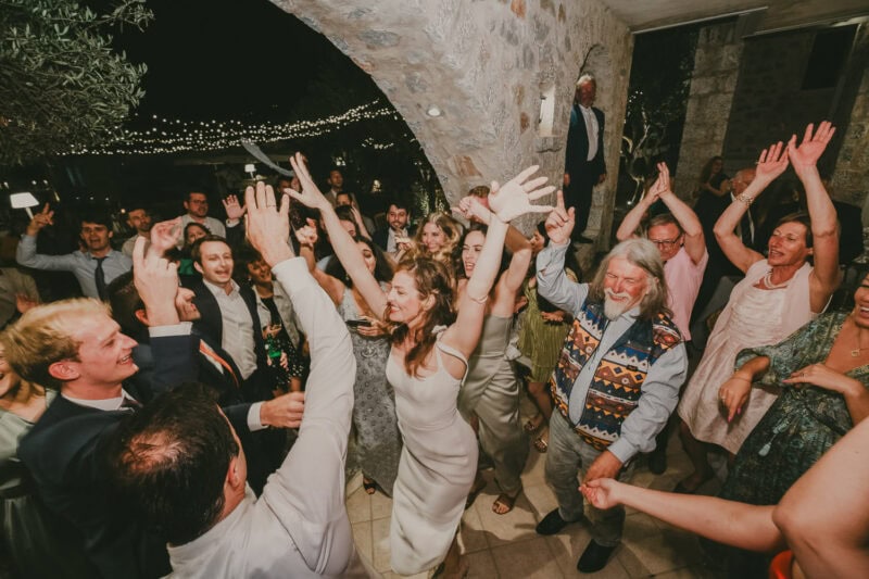 Energetic wedding party dancing under the lights in Mani